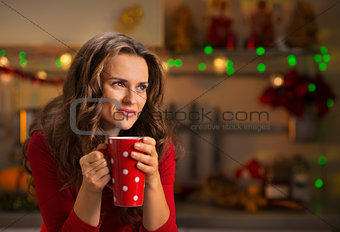 Woman having cup of hot chocolate in Christmas decorated kitchen