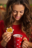 Woman having cup of chocolate and cookie in Christmas kitchen