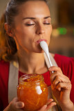 Young housewife tasting a spoon of homemade orange marmalade