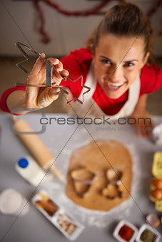 Housewife showing Christmas cookie cutter in kitchen. Closeup