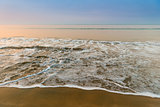 sea wave with foam on a sandy beach