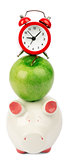 Fresh green apple with alarm clock and piggy bank