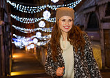 Stylishly dressed woman standing in front of Christmas lights