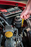 Car mechanic in auto repair service checking oil