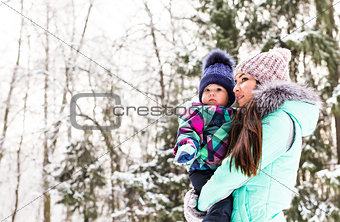 happy family mother and child baby daughter on a winter walk in the woods