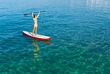 A beautiful and happy woman with arms up and learning paddle-sur