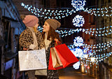 Mother and child with shopping bags among Christmas lights