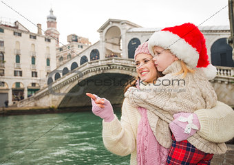 Mother pointing on something to child wearing Santa Hat, Venice