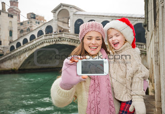 Happy mother and child in Santa Hat taking selfie in Venice