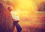Young Pregnant Woman Standing by the Haystack