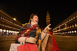 Woman with shopping bags pointing on something while in Venice