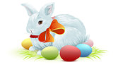 White easter bunny sitting on green grass. Bunny and colored Easter eggs