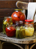 canned fruits and vegetables in jars on a wooden chair