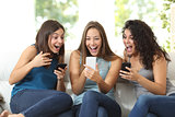 Three friends amazed watching a smart phone
