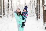 happy family mother and child baby daughter on a winter walk in the woods