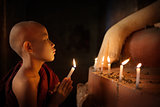 Buddhist novices praying with candlelight in temple