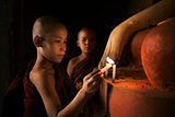 Buddhist novices praying with candlelight in monastery 