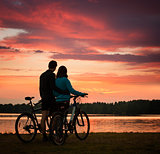 Couple with Bicycles Watching Sunset at River