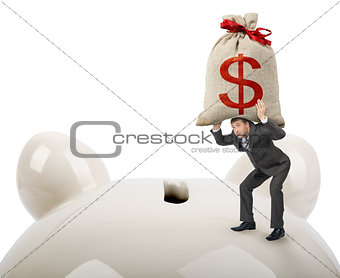 Businessman putting big money bag in piggy bank