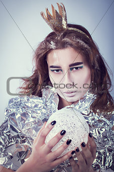 Portrait of pretty woman wrapped in foil with coronet looking forward standing on light grey background