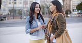 Two trendy young woman chatting in the street