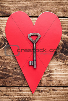 Love concept. Old key and a heart on wooden background