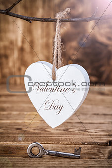 Love concept. Old key and a heart on wooden background