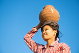 Young Asian traditional farmer carrying clay pot on head