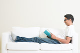 Asian man reading book on couch