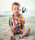 Child with phone and selfie stick on the beach