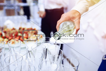 Waiter pours white wine in wineglass