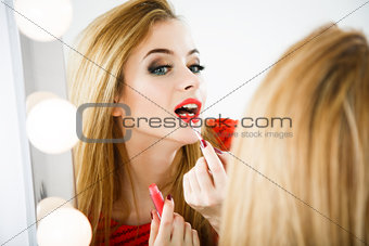 Beautiful Woman Applying Lipstick at the Mirror
