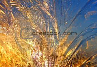 Sparkling ice-rich frosty pattern of thin ice on the window at sunset