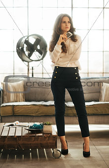 Stylish elegant woman in loft room holding smartphone