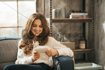 Stylisht woman is playing with smartphone sitting in loft room