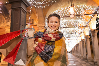 Woman with shopping bags standing under Christmas light, Venice