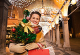 Happy woman with Christmas tree and shopping bags in Venice