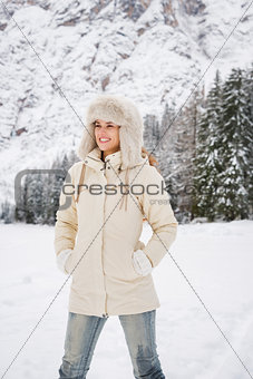 Woman in white coat and fur hat standing in winter outdoors