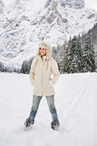 Woman in white coat and fur hat standing in winter outdoors