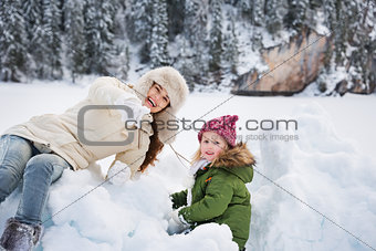 Happy mother pointing in camera to child while playing outdoors