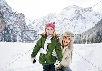 Smiling mother and child outdoors in front of snowy mountains