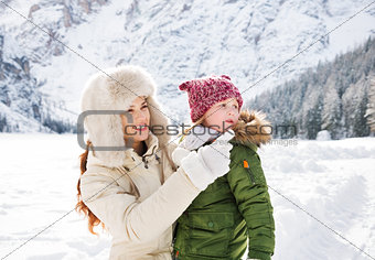 Mother pointing on something to child in winter outdoors