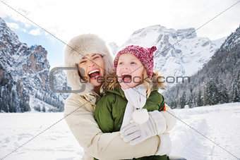Mother and child hugging outdoors in front of snowy mountains