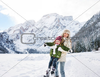 Mother and child playing outdoors in front of snowy mountains