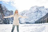Happy young woman standing in winter outdoors and rejoicing