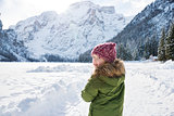 Child looking back while standing in front of snowy mountains