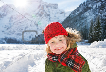 Smiling child standing in the front of snowy mountains