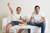 Men watching live sport game on tv at home
