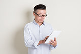 Portrait of mature Asian man using tablet pc