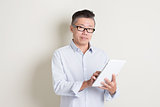 Portrait of mature Asian man using tablet computer